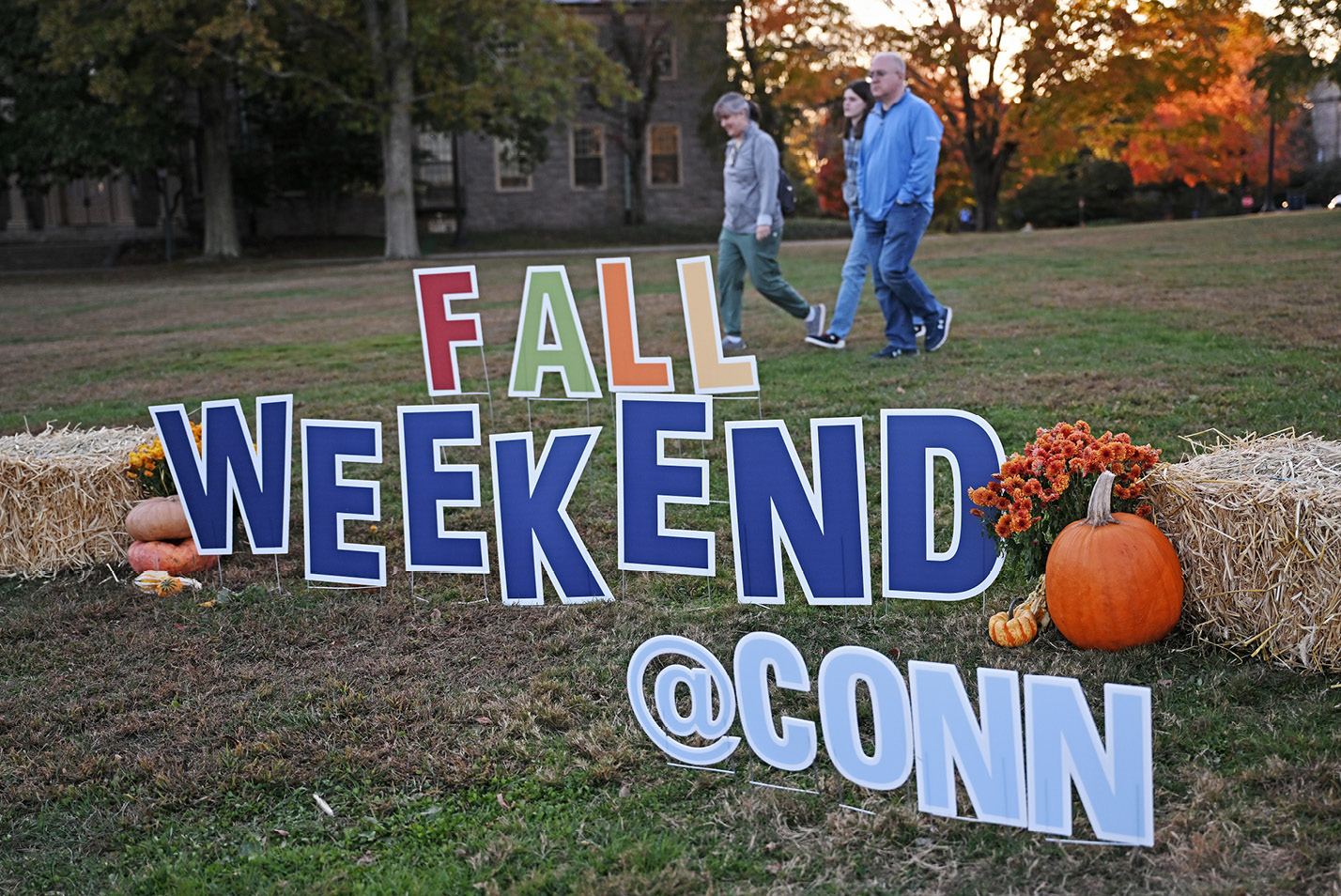 Family walks by Fall Weekend sign on the Green