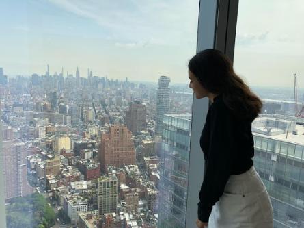 Dani looks out the window at the NYC skyline from the One World Trade Center