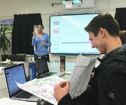 An Education student listens to a presentation by another student in the classroom. 