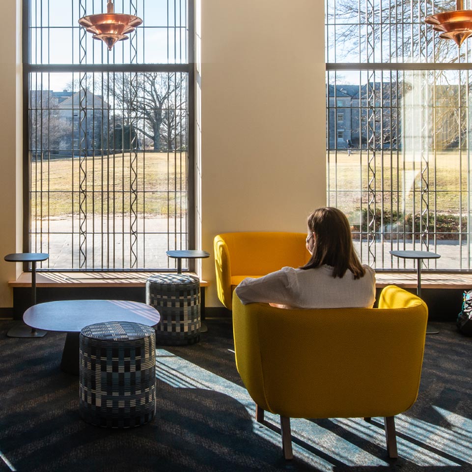 Student looking out of the green-side windows of the new Athey Center