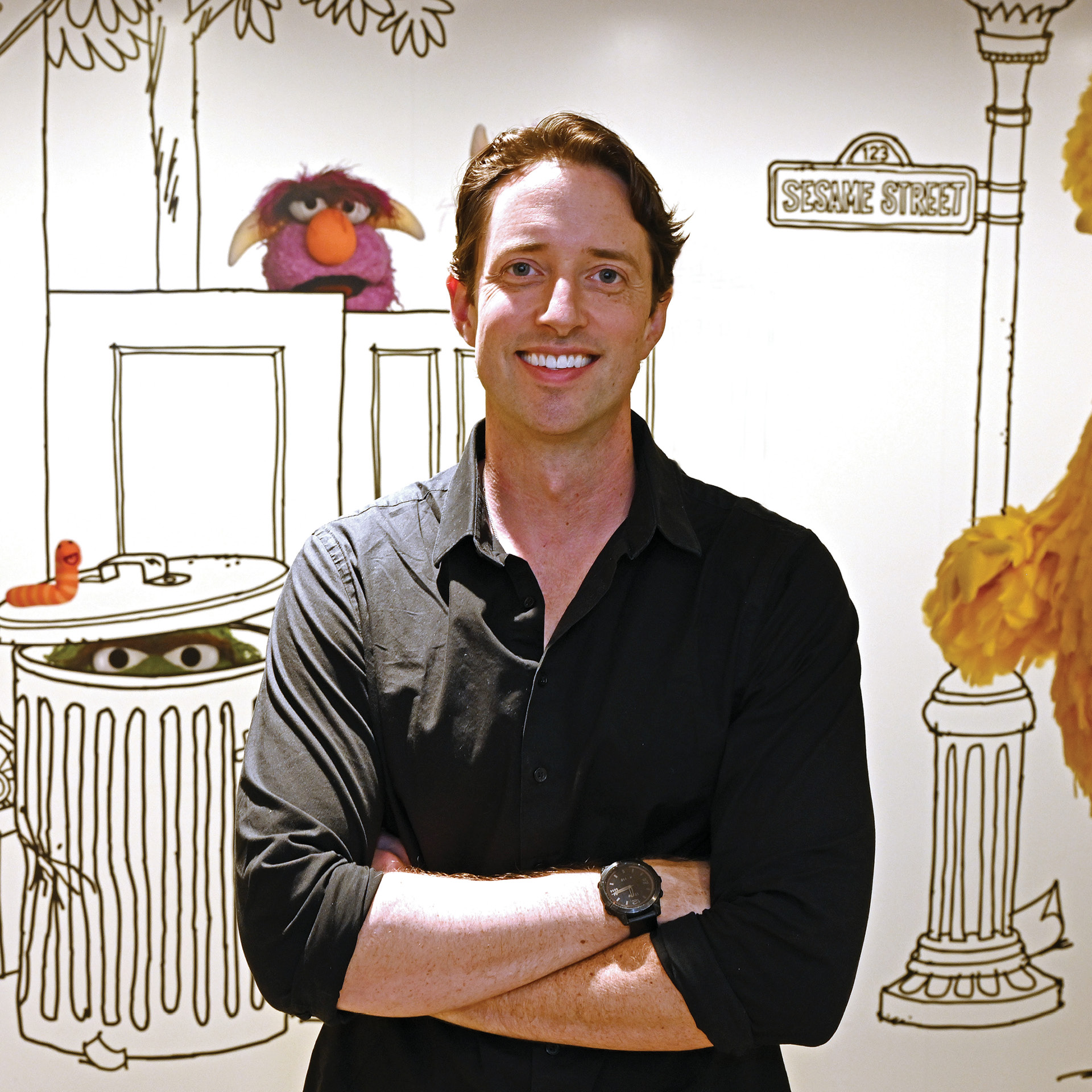 Image of TV producer Jordan Geary '04 in front of a large Sesame Street mural
