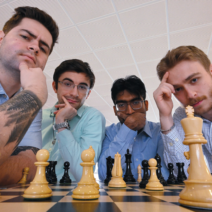 Image of four students around a chess board