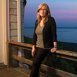 Seaside scenery: New York Times best-selling author Luanne Rice '77 poses on the deck of her cottage above Point O' Woods Beach in Old Lyme, Conn. The beachside community is the inspiration for the fictional Hubbard's Point, which serves as the setting for several of Rice's novels. Photo by Bob Handelman.