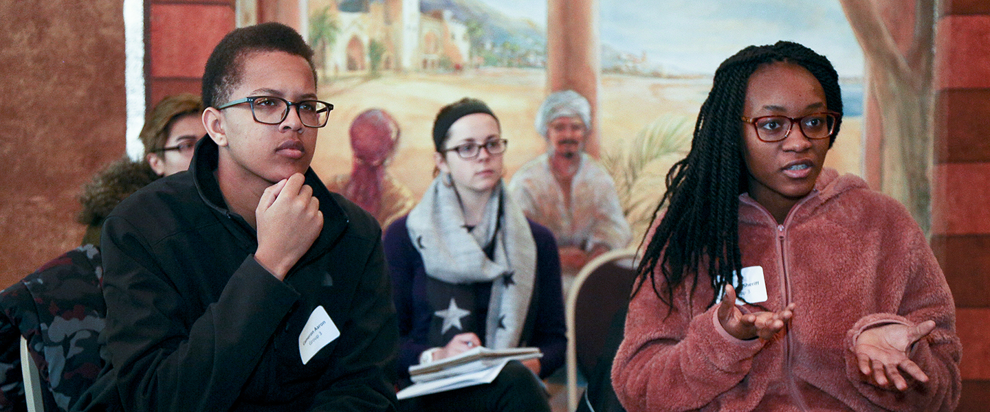 One student talks while another listens intently at the Emerging Leaders Conference. 