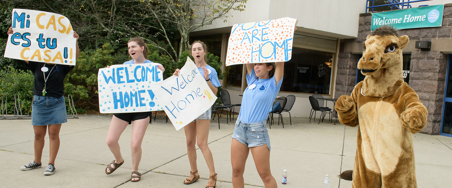 Student leaders welcome new students with signs and cheers.
