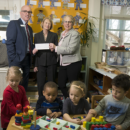 Representatives from Liberty Bank present a check to Kathryn O'Connor, director of the Children's Program, while preschool students play in front of them
