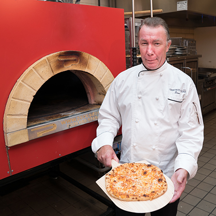 Chef Dave Perkins shows off a pizza made in the College's new pizza oven. 