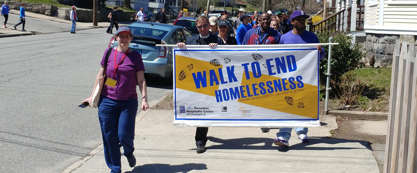 Walkers parade through New London holding the Walk to End Homelessness sign.