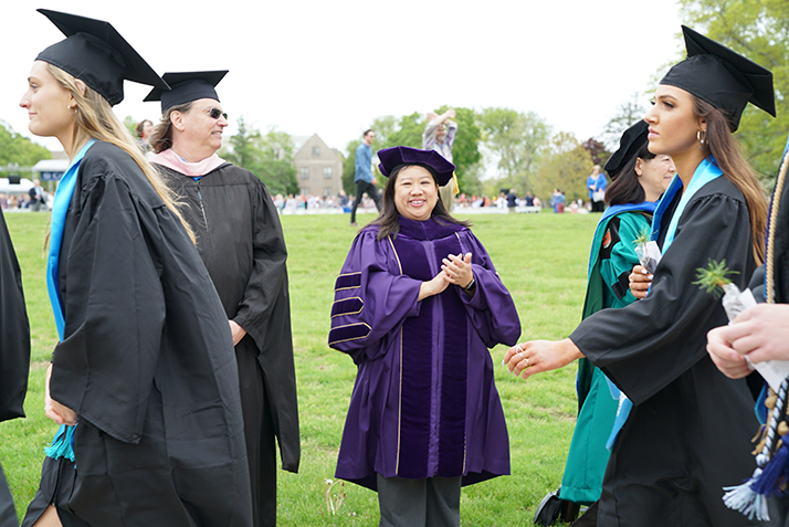 A faculty member cheers as members of the class process. 