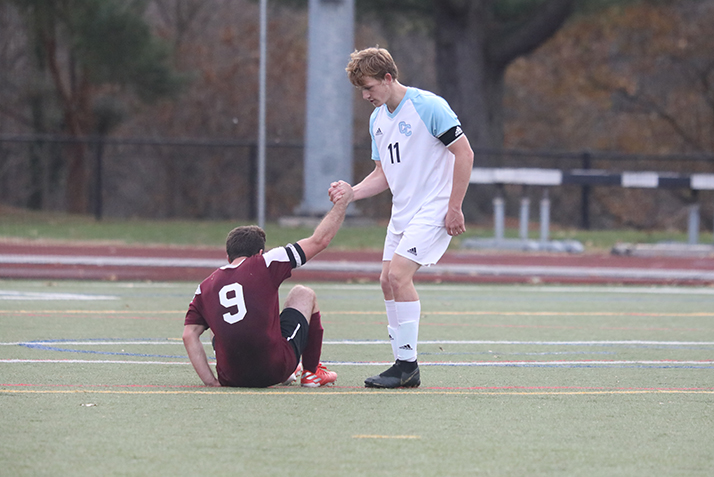 A Conn player helps a Swarthmore player up