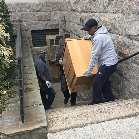 L-R: Connecticut College Facilities staff members Alexandher McQueen, Angelo Urena and Gamalier Berroa carry a dresser being donated to New London’s Homeless Hospitality Center for a new isolation center for people exhibiting symptoms of COVID-19. 
