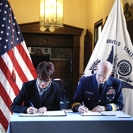 Connecticut College President Katherine Bergeron, left, and the superintendent of the U.S. Coast Guard Academy, Rear Admiral William G. Kelly, sign the new Memorandum of Agreement.