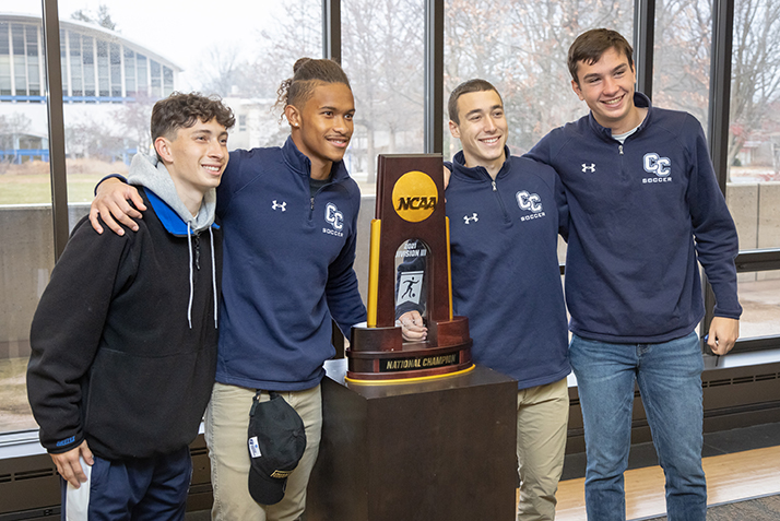 Members of the men’s soccer team pose with the NCAA Division III national championship trophy. 