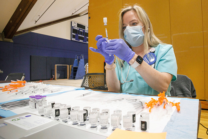 A nurse prepares COVID-19 vaccines for students at the campus clinic.