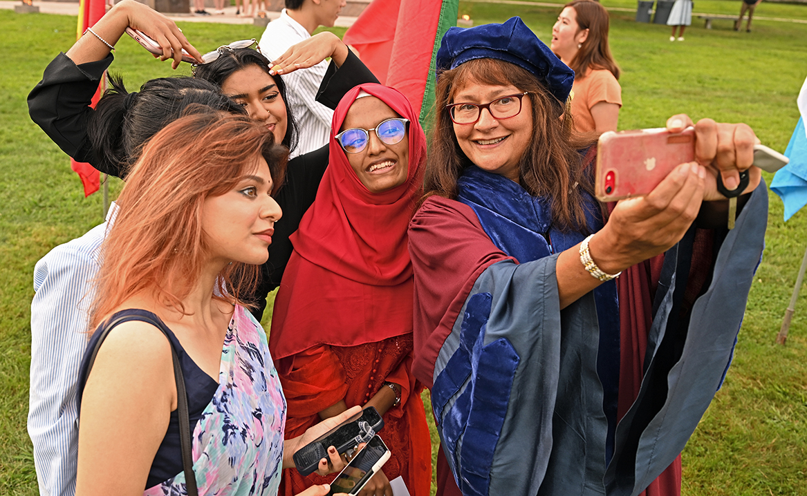 A professor takes selfies with students at Convocation.