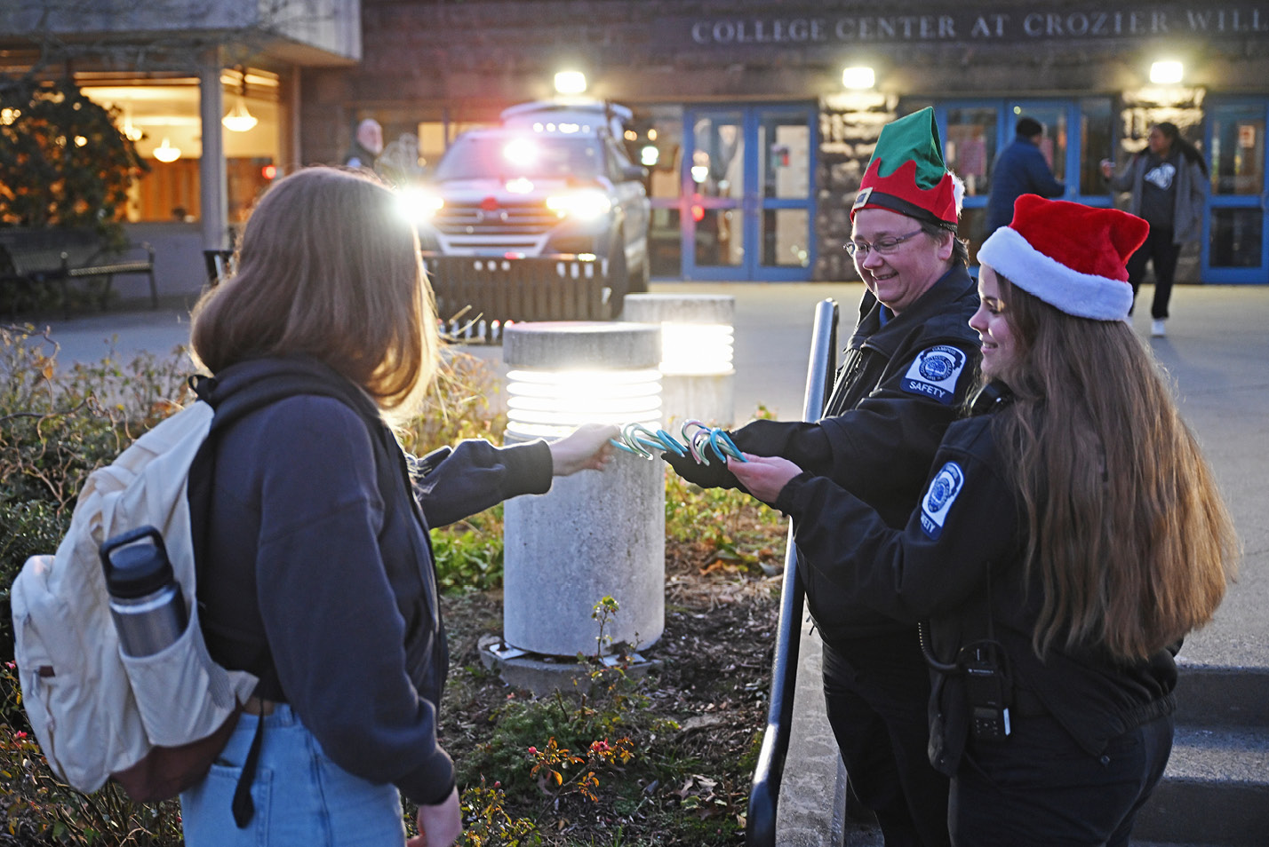 Campus safety workers handout candy canes in front of Cro.