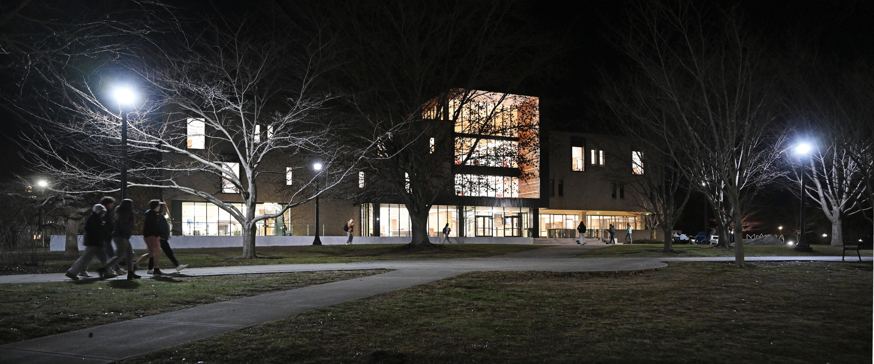 Students walk by Shain Library at night.