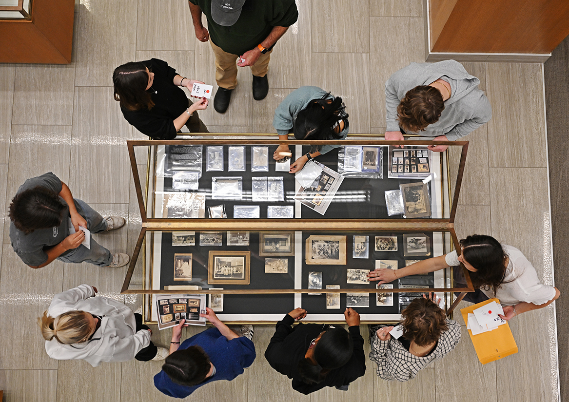 Students arrange photographs in a display case in Shain Library