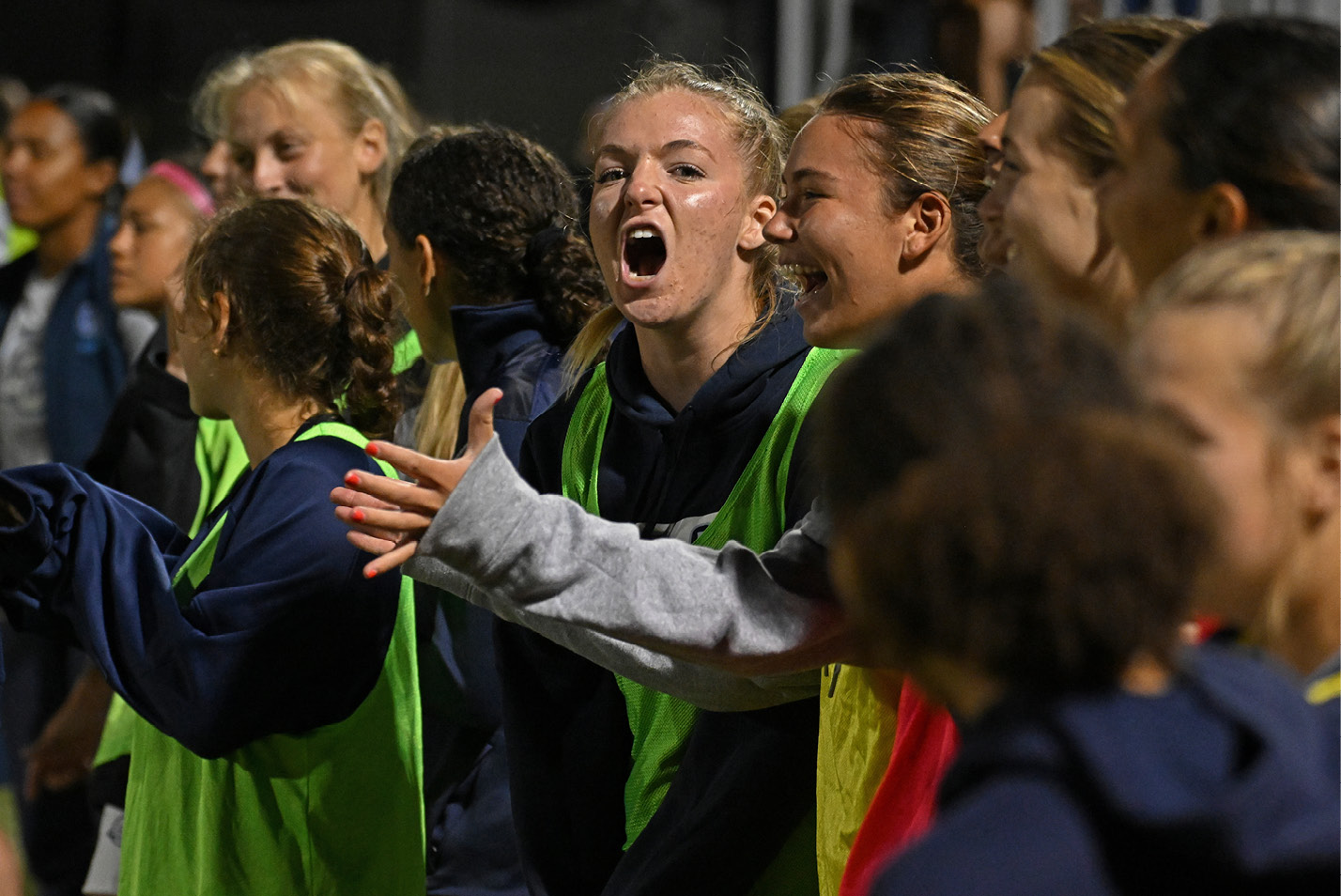 Women's soccer team cheers from the sidelines