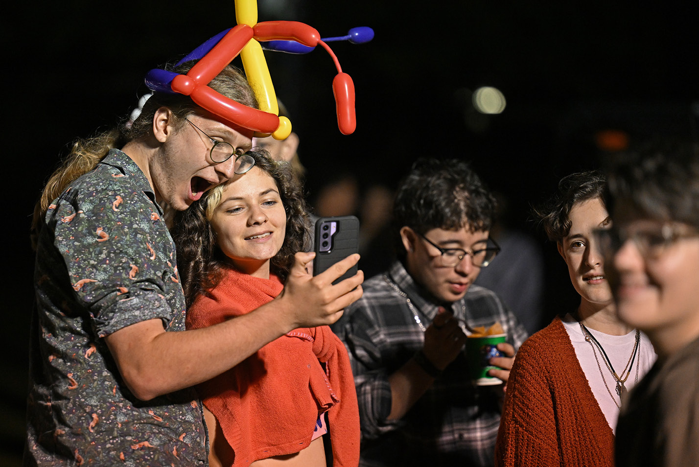 Students with balloon hats pose for selfies
