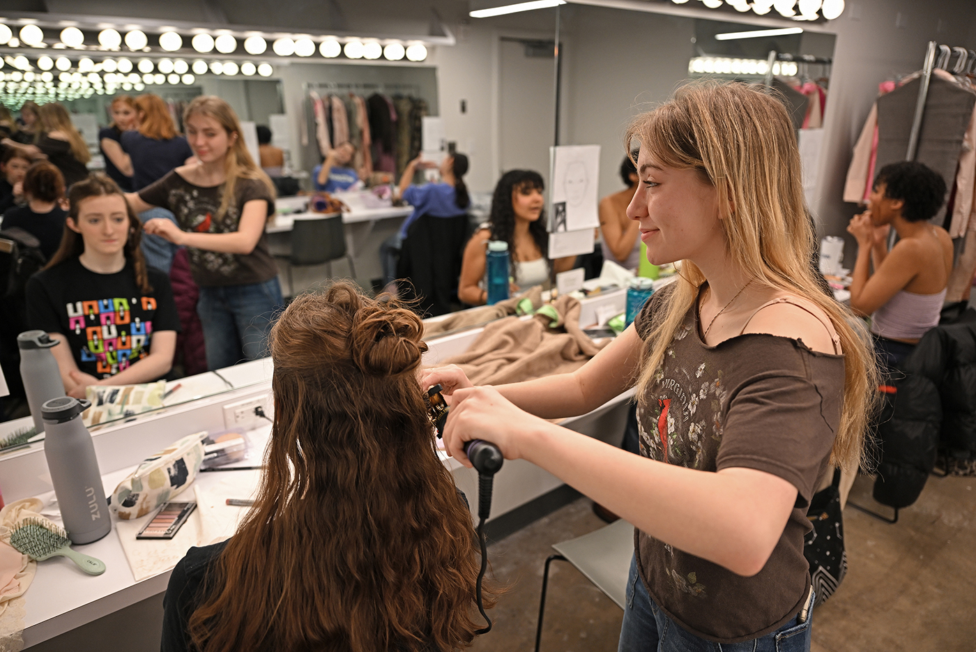 crew member curls hair of actress in dressing room
