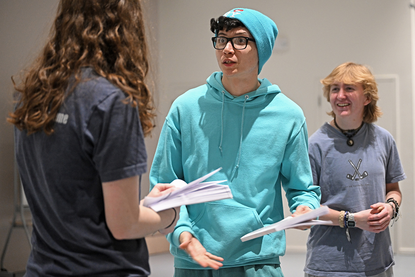 three actors rehearse scene with scripts in hand