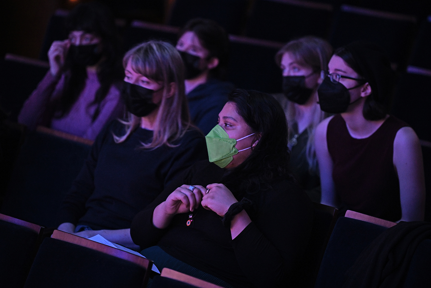 People sitting in theater seating in medical masks.
