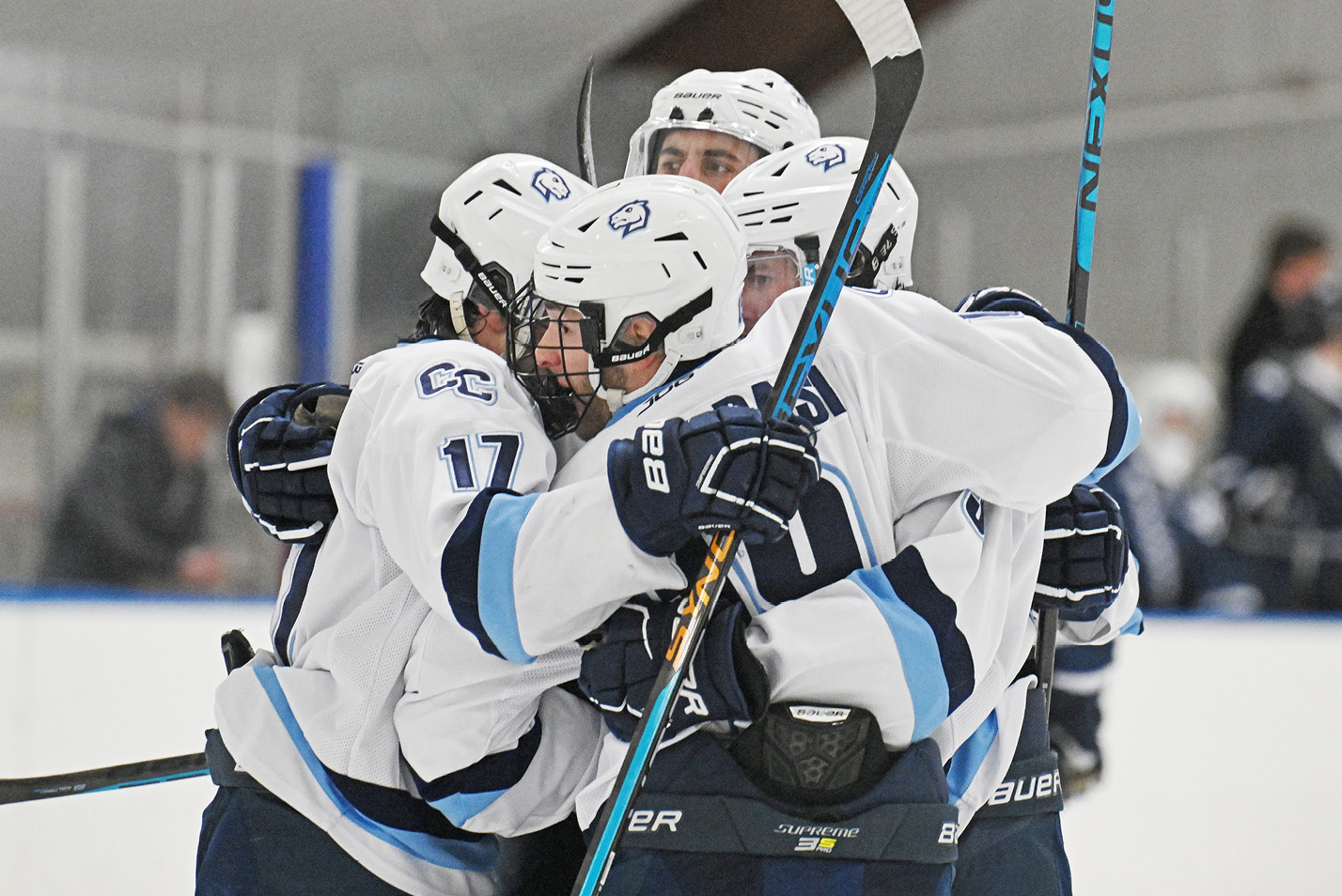 Men's hockey players huddle in celebration after a goal.