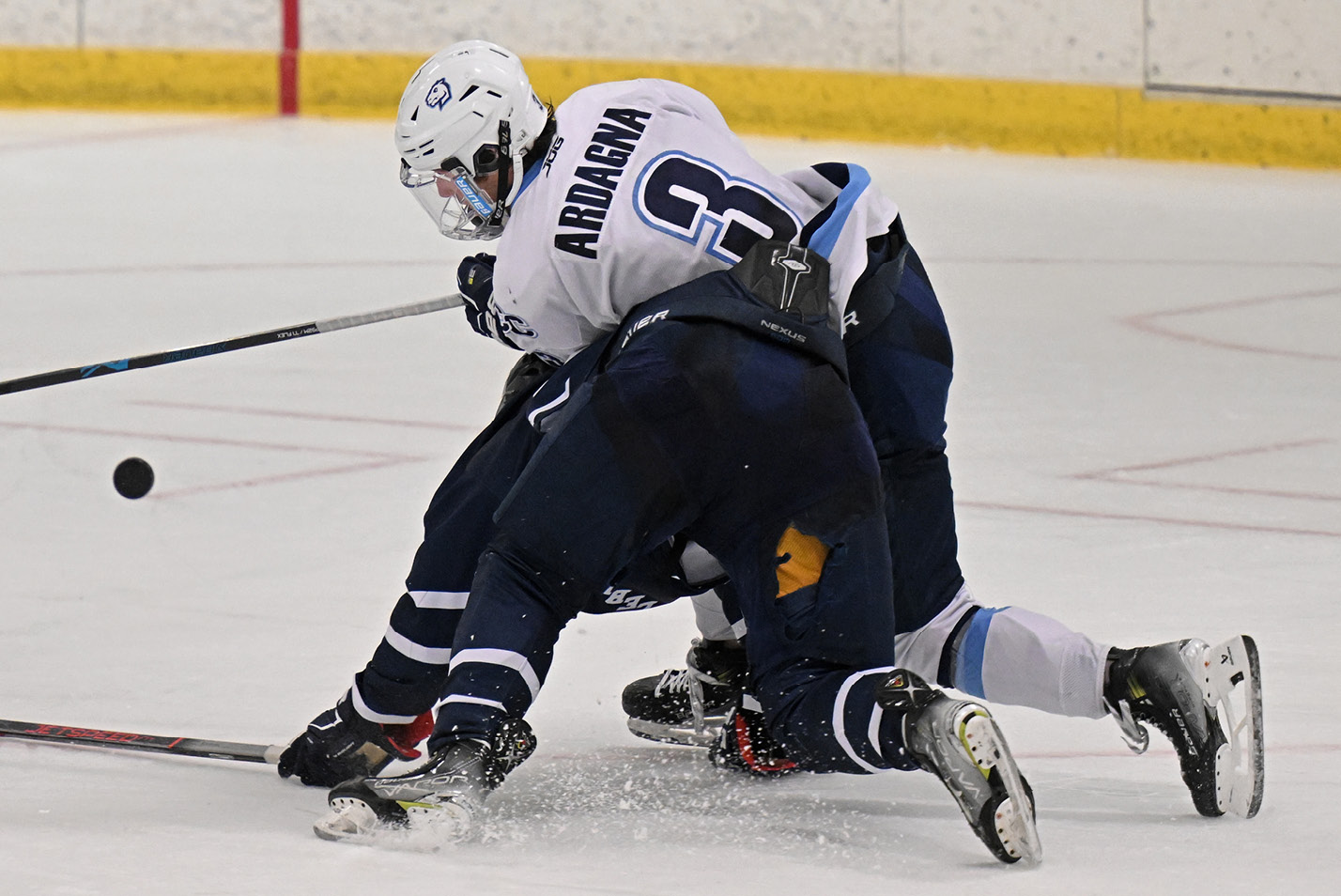 Men's hockey player crouches over an opponent vs. Middlebury
