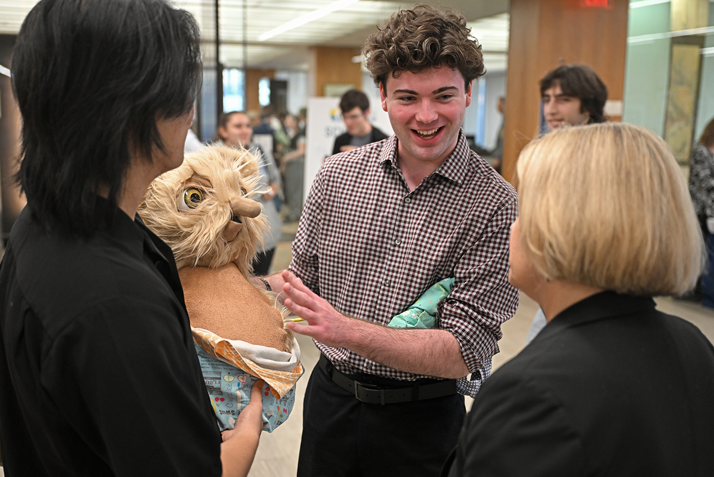 A student holds an animatronic puppet and explains its operation.