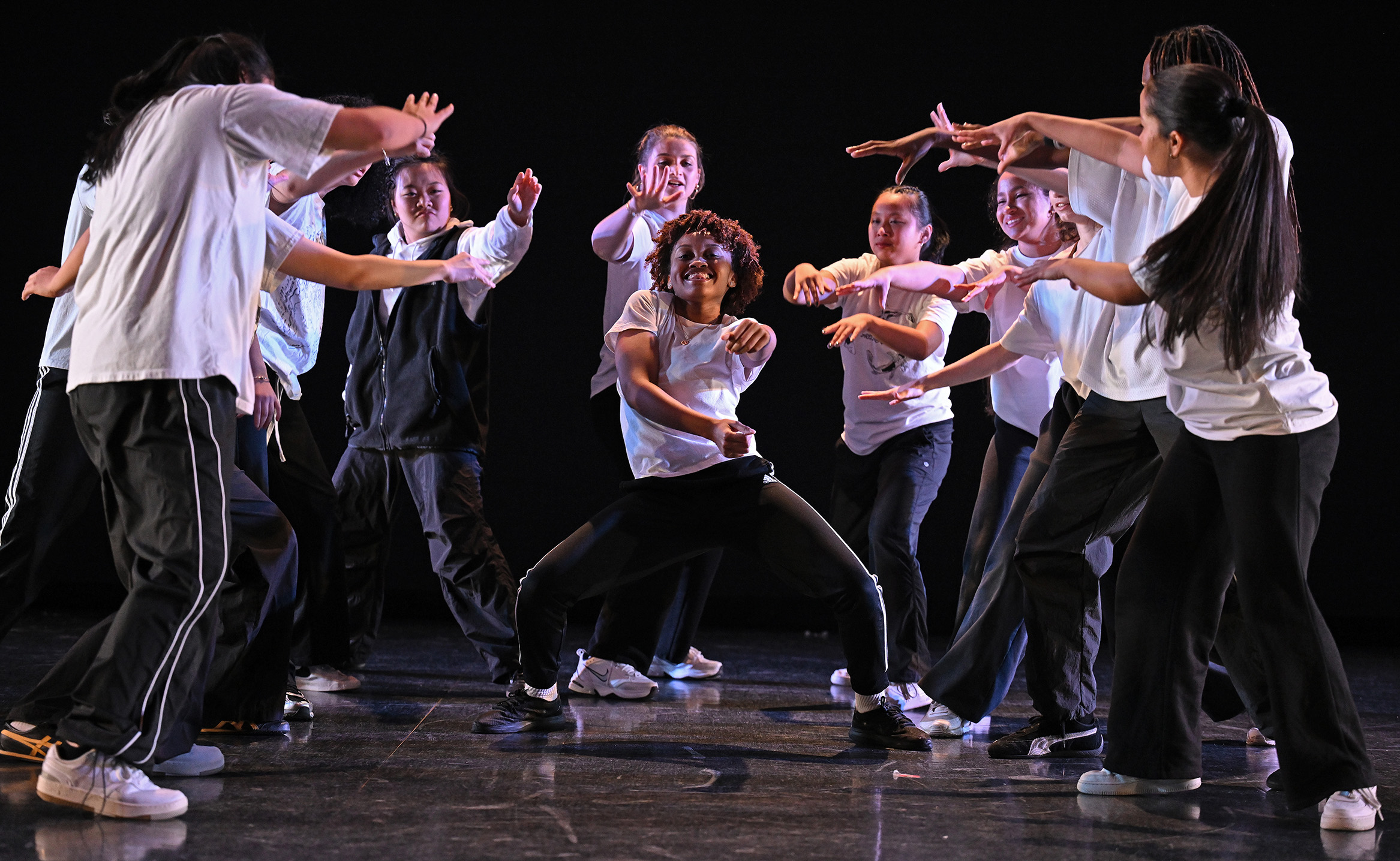 Student dancers wearing black and white perform a hip hop number on stage.