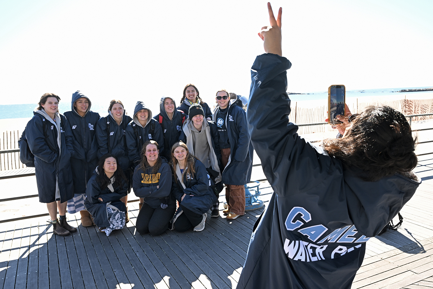 A group of student athletes take a group photo before participating in a polar plunge into the icy waters of Long Island Sound.