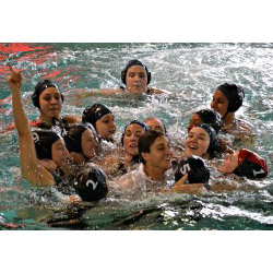 Members of the women's water polo team surround Coach JJ Addison in celebration moments after the team clinched its first league championship.